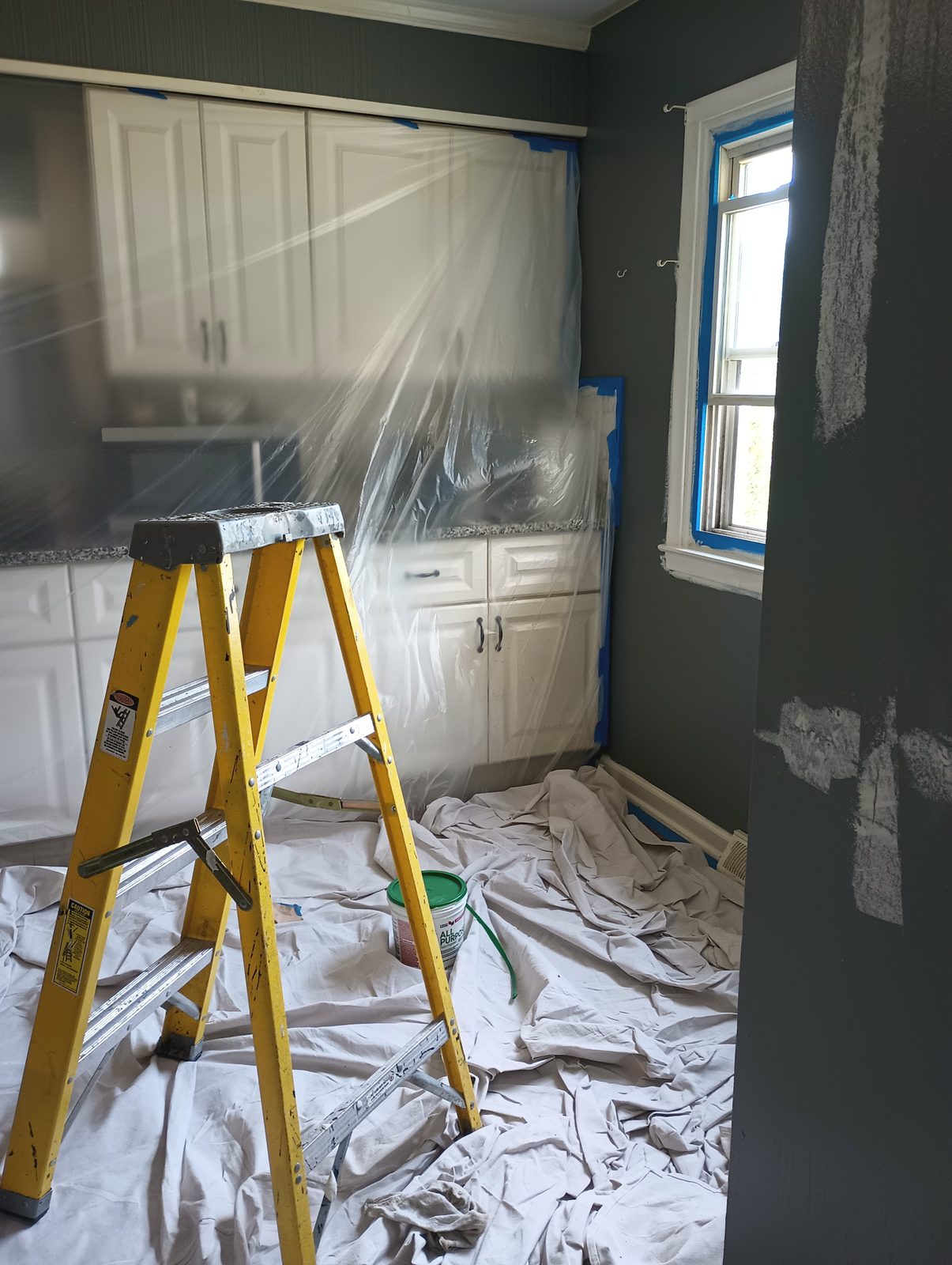 Kitchen before repaint, dark green walls, everything masked