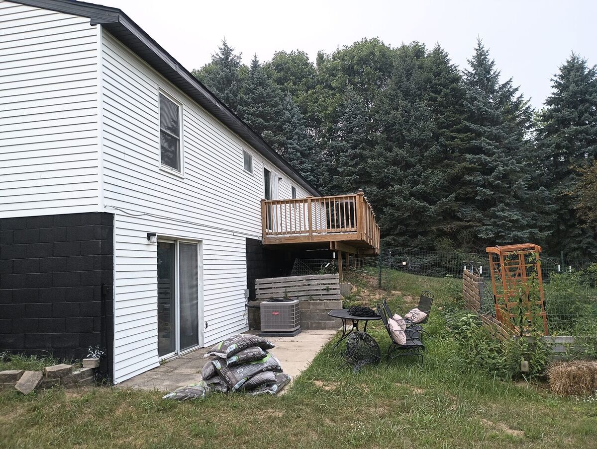 Back patio and deck after repaint, white upper siding with black lower block and trim