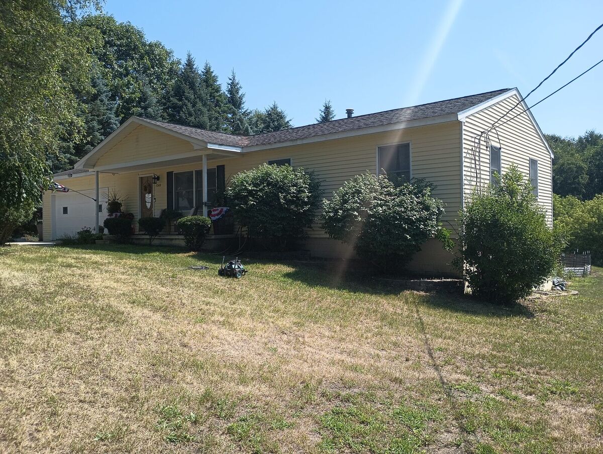 Same house front before repaint, dated yellow siding with black shutters